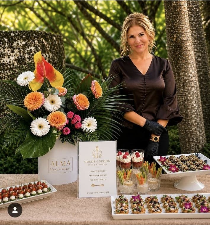 Victoria of Golden Spoon behind a plated appetizer display at an outdoor event.